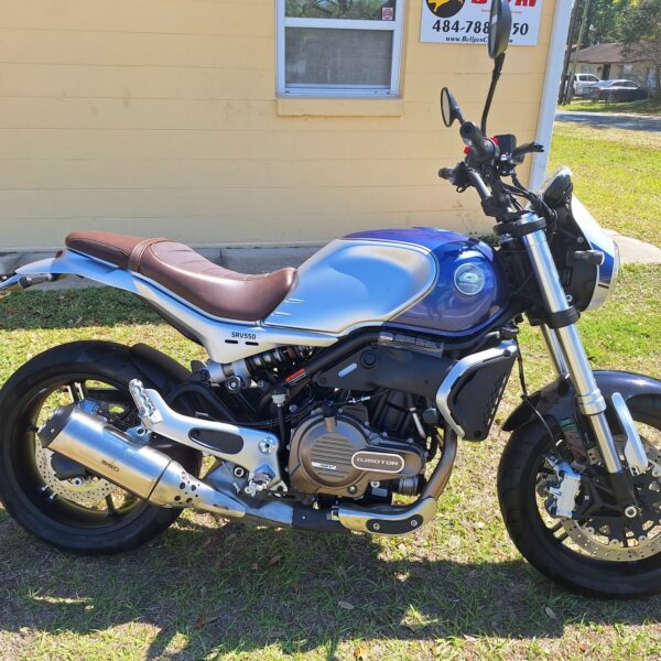 Blue motorcycle parked on grass beside yellow building