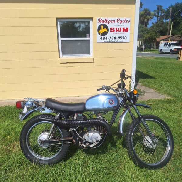 Vintage blue motorcycle parked beside yellow building